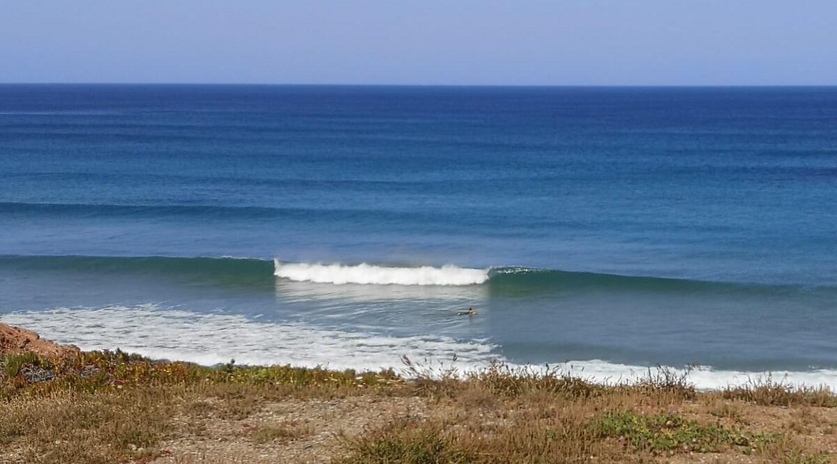 Vista da costa do Algarve — um surfista solitário na orla atlântica de Sagres
